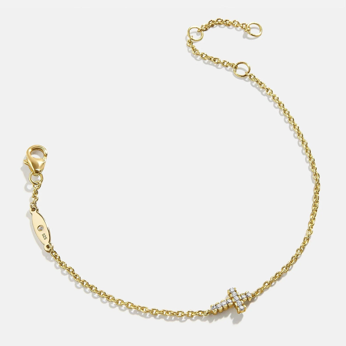 Lavisa 18K gold cross charm bracelet with cubic zirconia stones on display