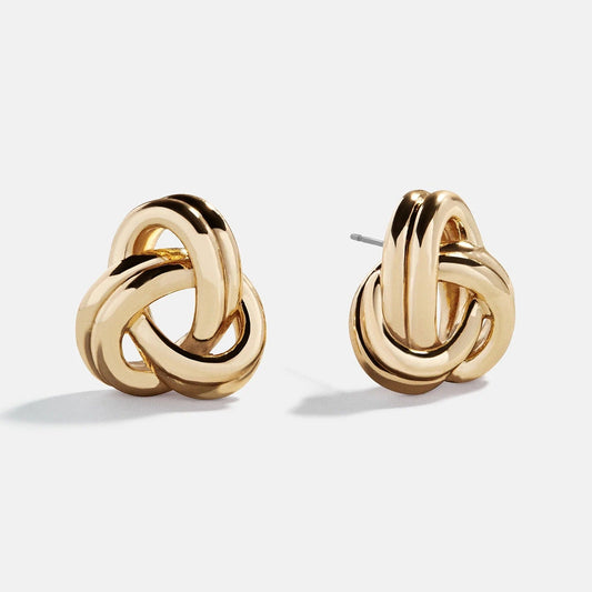 Lavisa glossy gold knot statement earrings resting on a neutral surface