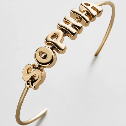 Lavisa custom gold bubble letter cuff bracelet worn on a wrist