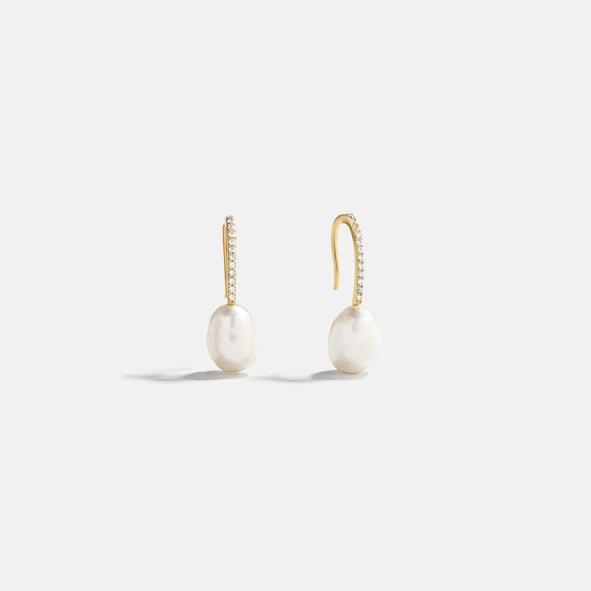 Lavisa gold pearl drop earrings with pavé hook on a neutral background