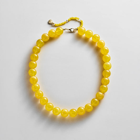 Lavisa yellow resin beaded necklace resting flat on a white background