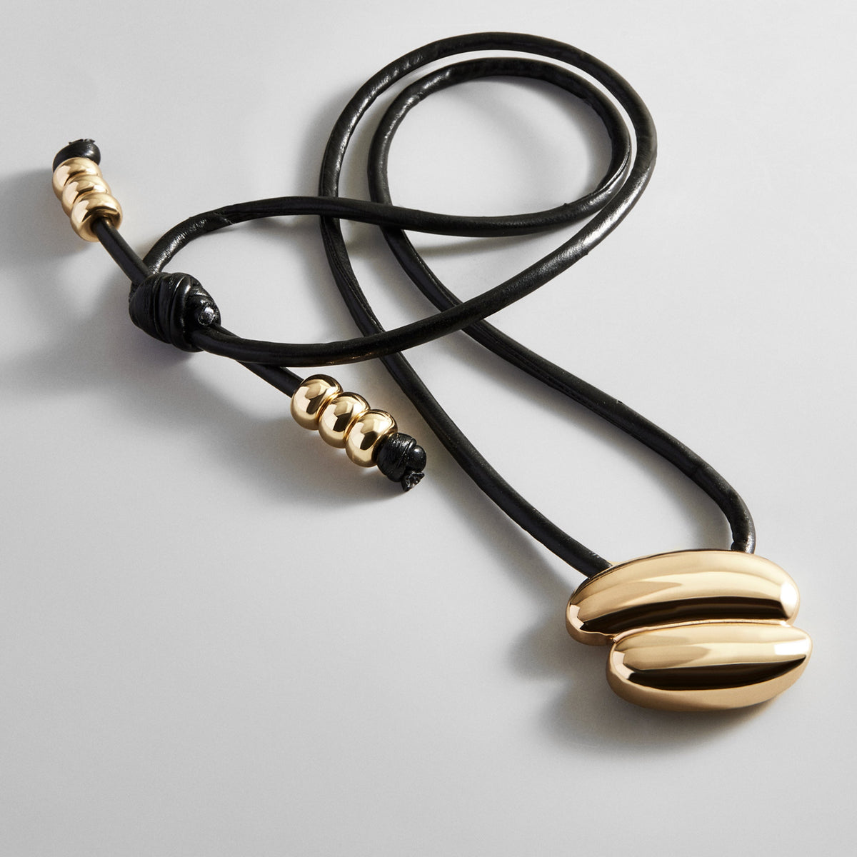 Lavisa asymmetrical gold pendant on an adjustable black cord necklace