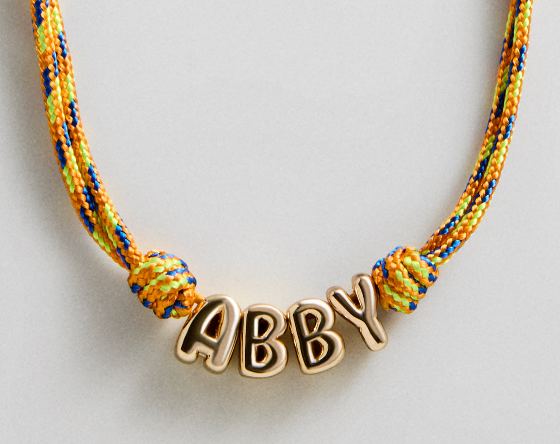 Lavisa custom bubble letter necklace with gold letters on a colorful paracord base.