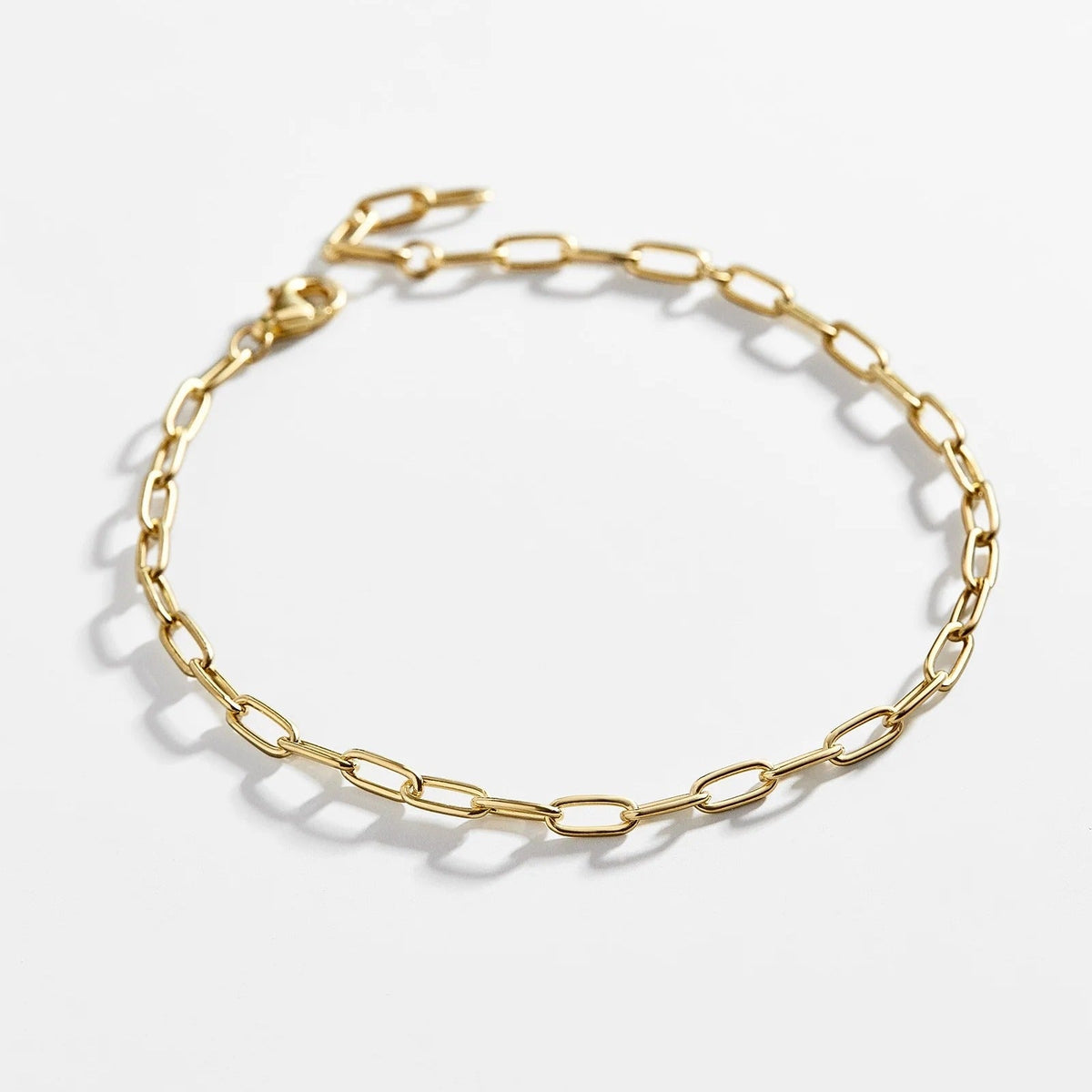 Lavisa delicate 14K gold paperclip chain bracelet laid flat on a neutral background