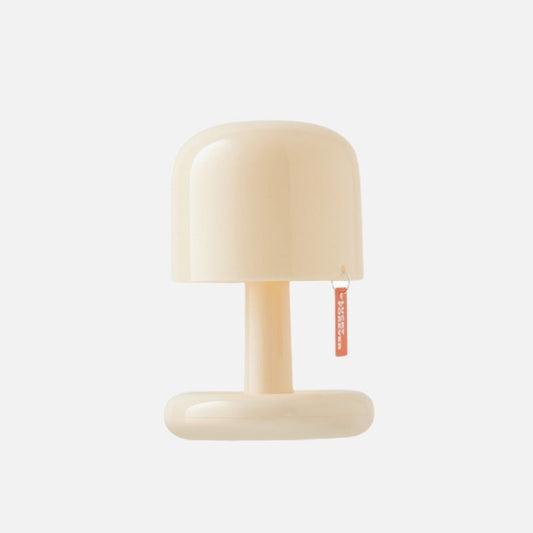 Lavisa mini mushroom cordless table lamp in ivory emitting warm ambient light on a bedside table